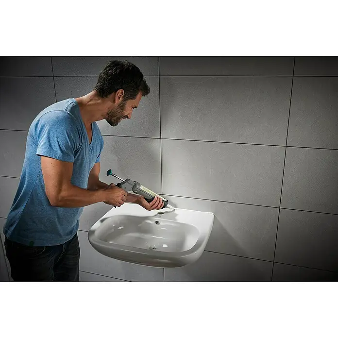 Wolfcraft Kartuschenpresse MG 211 ERGO - Passend für: 310 ml Kartuschen Ø 50 x 225 mm, Acryl - Ein Mann verwendet eine Kartuschenpistole, um die Spüle im Badezimmer abzudichten. Präzise und saubere Arbeit für ein perfektes Ergebnis.