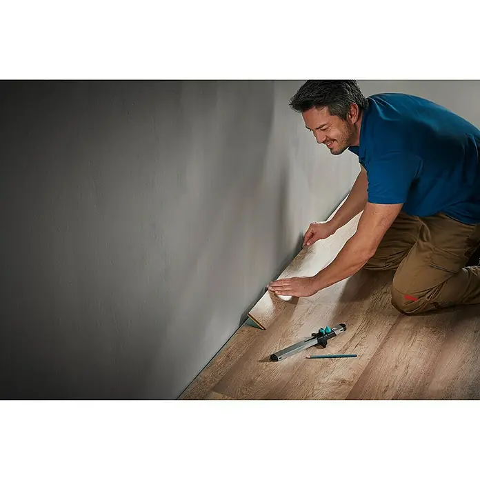 Wolfcraft Anreißlehre - Länge: 295 mm - Mann verlegt mit Werkzeug ein Laminatboden und passt diesen an einer Wand an. Das Werkzeug erleichtert die genaue Anpassung.