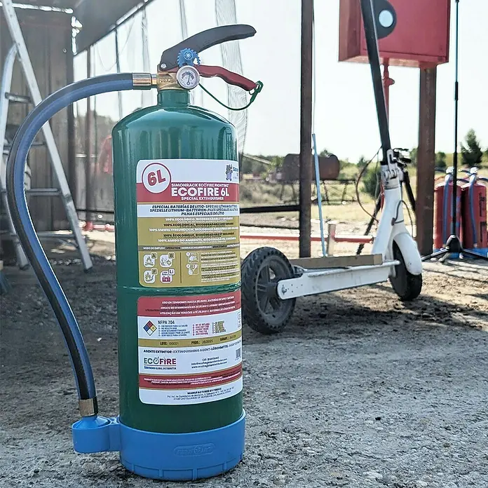 Simonrack Ecofire Extintor de incendios Fighting con gancho - 6 l - Primer plano de un extintor verde EcoFire 6L con base azul, para incendios de baterías de litio, en exteriores.