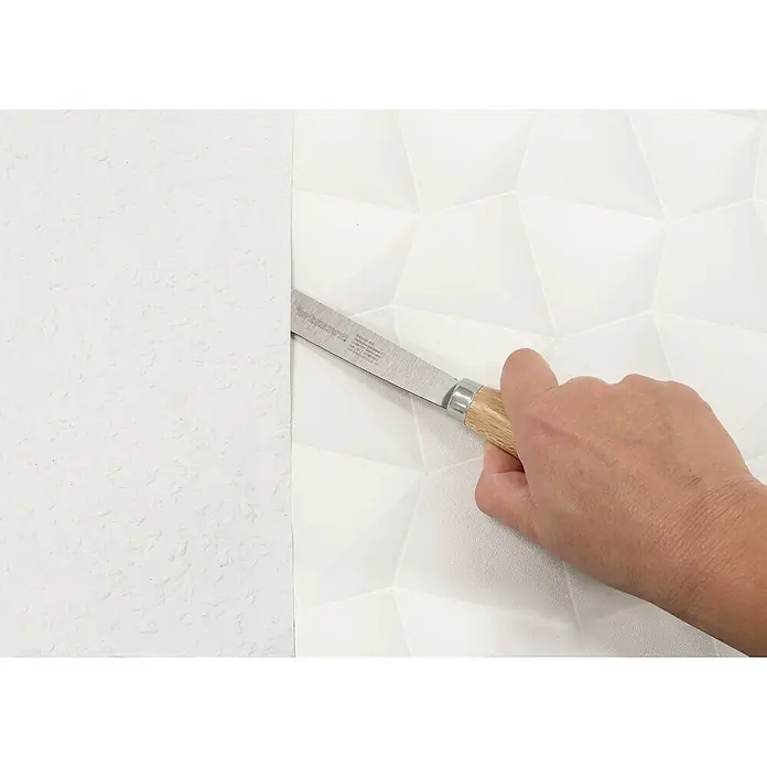 Wisent Malerspachtel - Klingenbreite: 28 mm - Nahaufnahme eines Messers mit Holzgriff, das zum Zuschneiden von Tapeten vor einer weißen, geometrisch gemusterten Wand verwendet wird.
