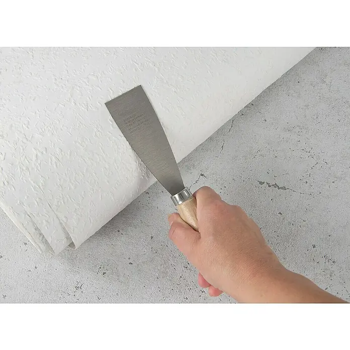 Wisent Malerspachtel - Klingenbreite: 40 mm - Hand hält einen Spachtel vor einer Rolle weißer Tapete. Das Werkzeug dient zum Glätten der Tapete und sorgt für ein sauberes Ergebnis.