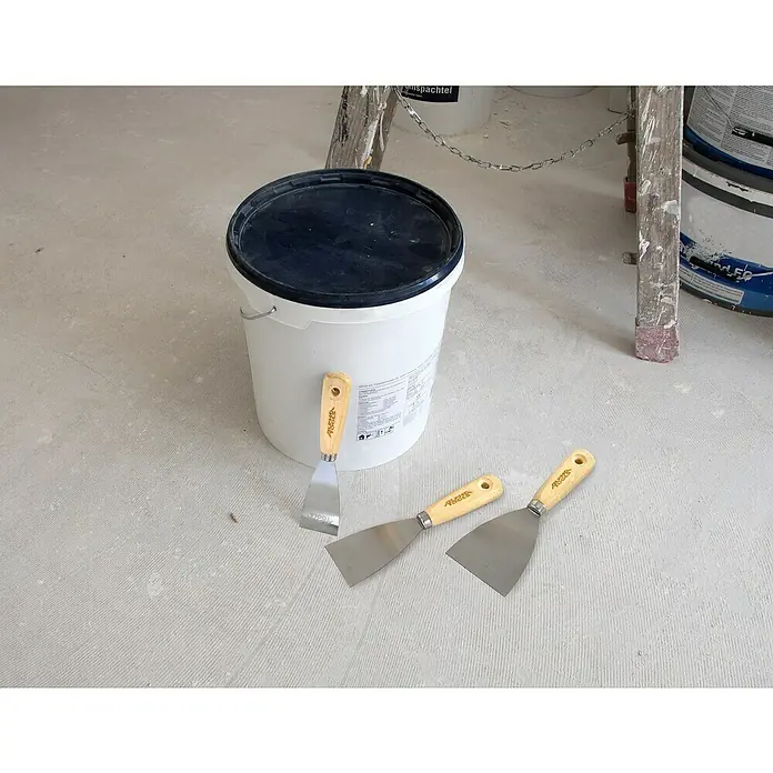 Alpha Tools Spachtel-Set - 3 -tlg. - Ein weißer Eimer mit schwarzem Deckel und drei Spachteln mit Holzgriffen liegen auf einem grauen Boden.