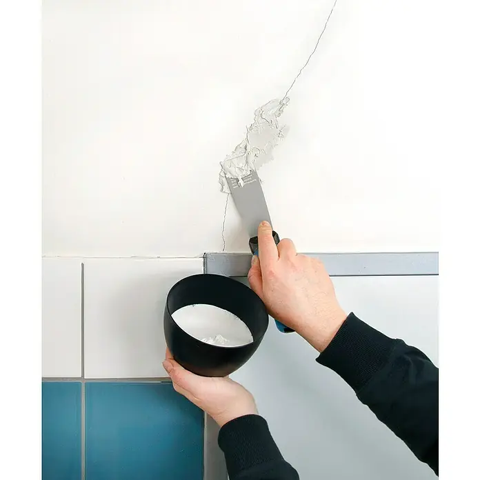 Wisent Malerspachtel mit Softgriff - Klingenbreite: 40 mm - Eine Person, die mit einer Spachtel und Spachtelmasse ein Loch in einer Wand füllt, wobei der Fokus auf dem Werkzeug und der Reparatur liegt.