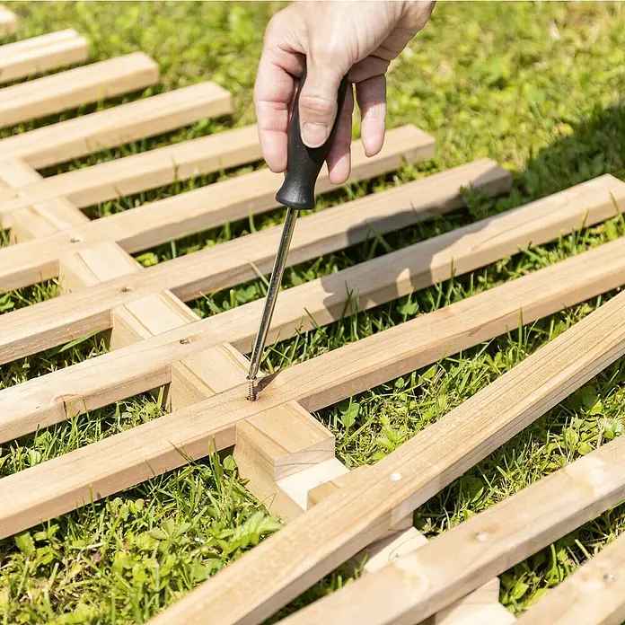 Rankhilfe - B x H: 70 x 119 cm, Holz, Braun - Befestigen Sie Holzlatten mit einem Schraubenzieher auf einer Rasenfläche. Die Holzkonstruktion ist in der Nahaufnahme gut zu erkennen.