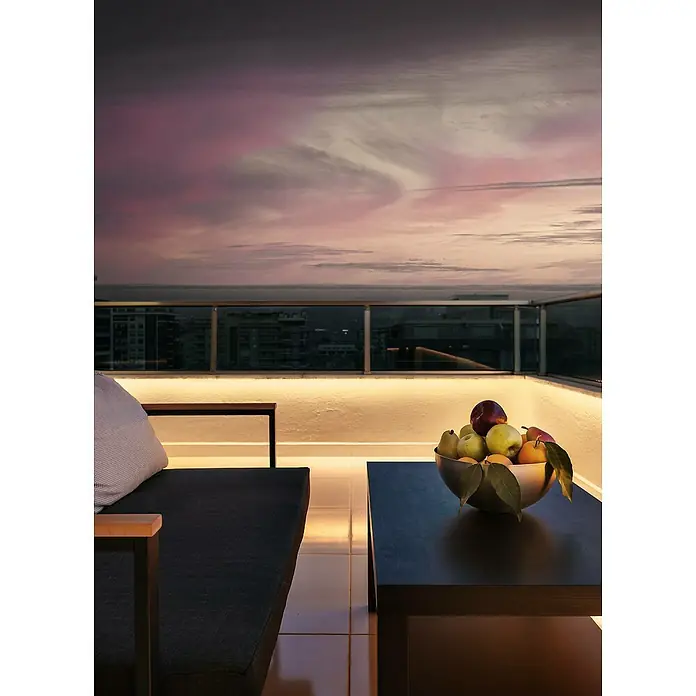 Eglo Connect LED-Stripes Flatneon Z - Länge: 5 m, 3.400 lm, RGBW - Ein stilvoller Tisch mit einer Schale voller frischer Früchte auf einer Dachterrasse mit Blick auf den Sonnenuntergang.
