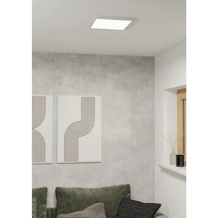 Eglo connect.z LED-Panel Fueva 6-Z - 13,5 W, L x B x H: 29 x 29 x 2,5 cm, Weiß, RGBW - Modernes Zimmer mit einer quadratischen LED-Deckenleuchte, die helles Licht spendet. Minimalistische Kunstwerke und ein grünes Sofa runden das Interieur ab.