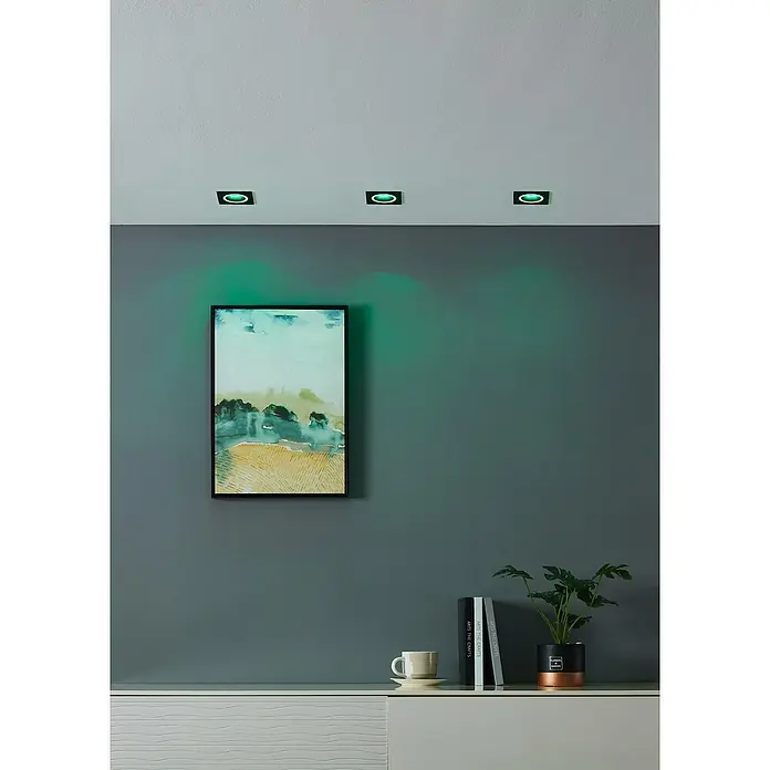 Eglo Connect LED-Einbauleuchte Carosso-Z - 4,7 W, L x B x H: 9,3 x 9,3 x 9 cm, Schwarz, RGBW - Zimmerdecke mit drei quadratischen, eingelassenen grünen Strahlern, die die Wandakzente hervorheben und ein Kunstwerk beleuchten.
