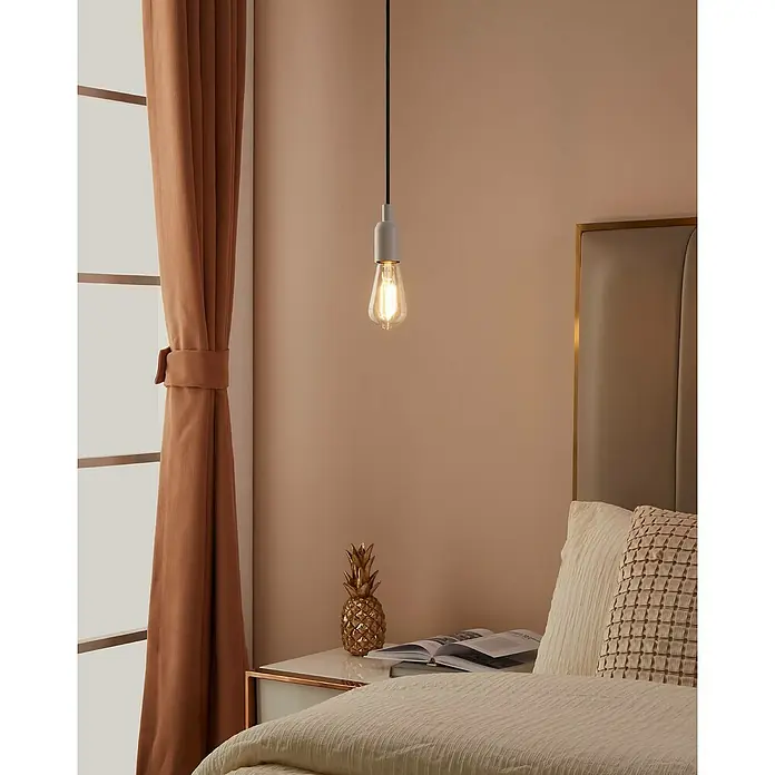 Eglo connect.z Smart-LED-Lampe ST64 - E27, Dimmbar, Warmweiß, 806 lm, 6 W - Eine moderne Pendelleuchte mit Edison-Glühbirne hängt über einem Nachttisch mit goldenem Ananas-Dekor.