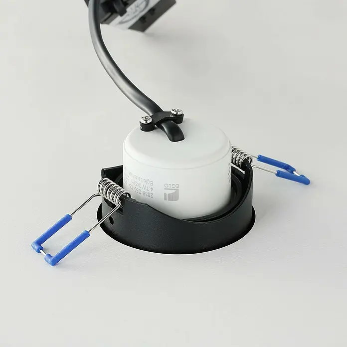 Eglo LED-Einbauleuchte rund Saliceto-Z - Ø x H: 88 x 46 mm, Schwarz, 1 Stk. - Nahaufnahme einer EGLO Deckeneinbauleuchte in Schwarz und Weiß mit blauen Halteklammern, die auf einer ebenen Fläche steht.