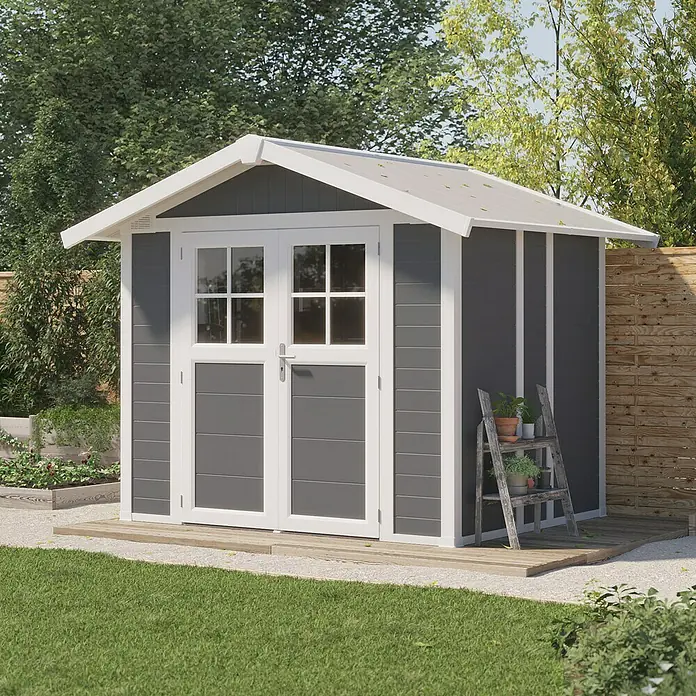 Grosfillex Caseta para jardín Deco - Medidas ext. (An x Pr): 295 x 261 cm, Plástico, Gris oscuro, 4,9 m² - Una caseta de jardín gris con puertas dobles y marcos blancos, rodeada de vegetación. Ideal para guardar herramientas y un toque elegante.