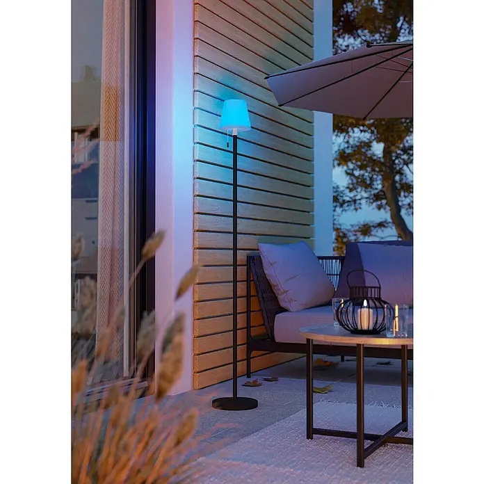 Eglo Solar-Stehleuchte Montapalma-L - Schwarz/ Weiß, IP44, Ø x H: 15 x 140 cm - Stimmungsvolle Außenaufnahme mit einer eleganten, blau leuchtenden Stehlampe, die eine moderne Terrasse mit gemütlicher Atmosphäre beleuchtet.