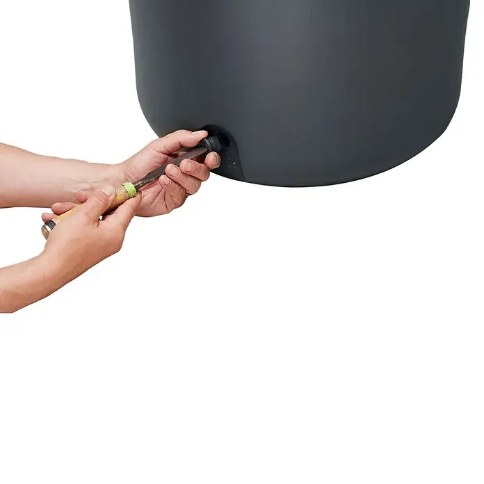 Garantia Regenspeicher Azura 2in1 - 340 l, Graphite - Nahaufnahme von Händen, die mit einem Werkzeug an einem grauen Regenfass arbeiten. Fokus auf die Montage des Wasserbehälters.