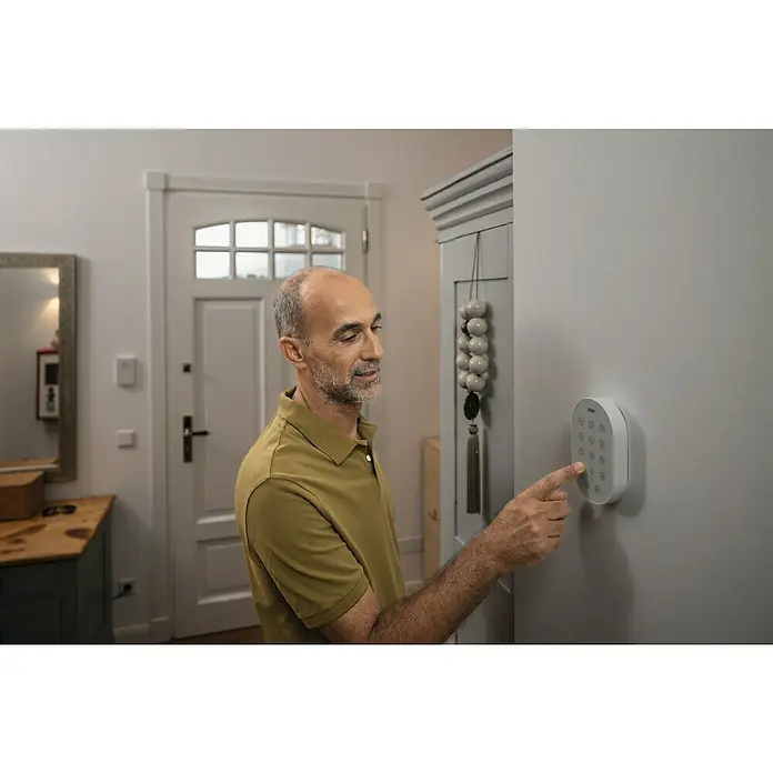 Abus Alarmanlagen-Bedienelement Smartvest Pro FUBE45010 - Passend für: Funk-Alarmanlage Smartvest Pro, L x B x H: 128 x 78 x 158 mm - Ein Mann bedient ein smartes Alarmsystem an der Wand, um die Sicherheit des Hauses zu gewährleisten.