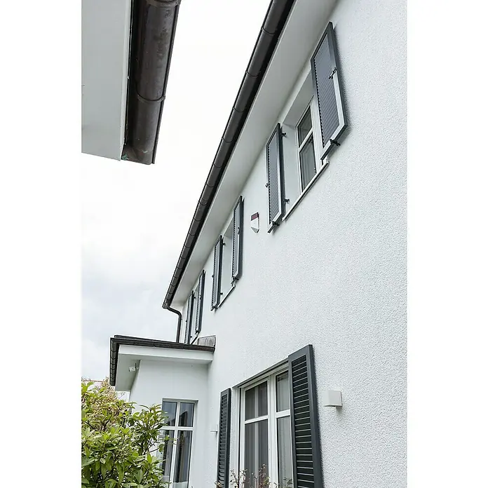 Abus Alarmsirene Smartvest Pro FUSG45000 - Außen, 105 dB - Fassade eines Hauses mit grauen Fensterläden, die teilweise geöffnet sind, und einer weißen Wand mit rauer Textur.