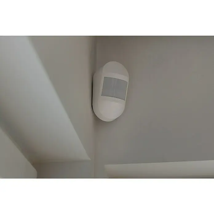 Abus Alarmanlagen-Bewegungsmelder Smartvest Pro FUBW45000 - Reichweite ca.: 100 m - Die Aufnahme zeigt einen weißen Bewegungsmelder an einer hellgrauen Wand, der sich an der Ecke zu einer Wandbefestigung befindet.