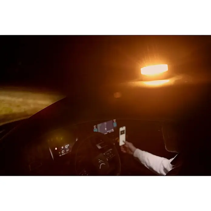 Luz de emergencia Help Flash IoT+ - Apto para: Avería en el vehículo - Interior de un coche de noche iluminado por una brillante luz de techo. Una persona sostiene un teléfono.