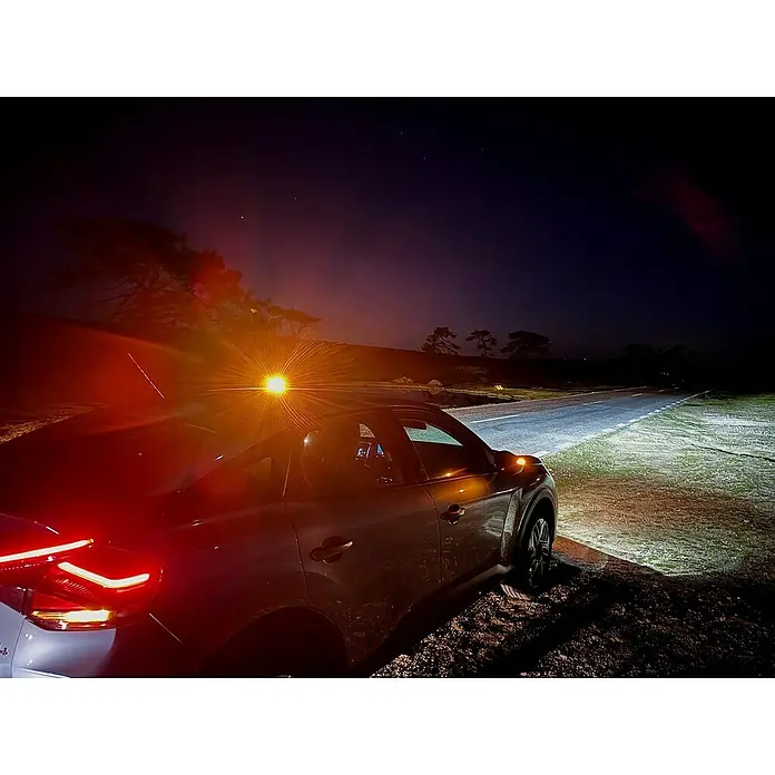 Luz de emergencia Help Flash IoT+ - Apto para: Avería en el vehículo - Foto nocturna de un coche plateado aparcado en una carretera rural oscura, iluminado por los faros del vehículo.
