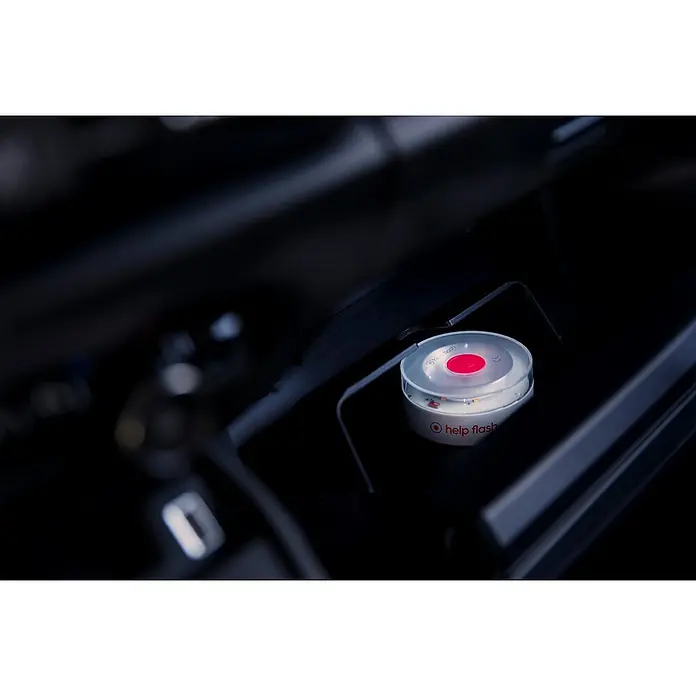 Luz de emergencia Help Flash IoT+ - Apto para: Avería en el vehículo - Una luz LED de emergencia llamada "help flash" se encuentra en un compartimento oscuro, lista para su uso en caso de averías o emergencias.