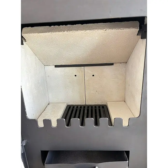Domofire Kaminofen Napoli II - 6 kW, Material Verkleidung: Keramik, Weiß - Nahaufnahme eines Kaminofens mit Schamottsteinen und einem Rost für Holzscheite. Der Ofen ist aus grauem Metall gefertigt.