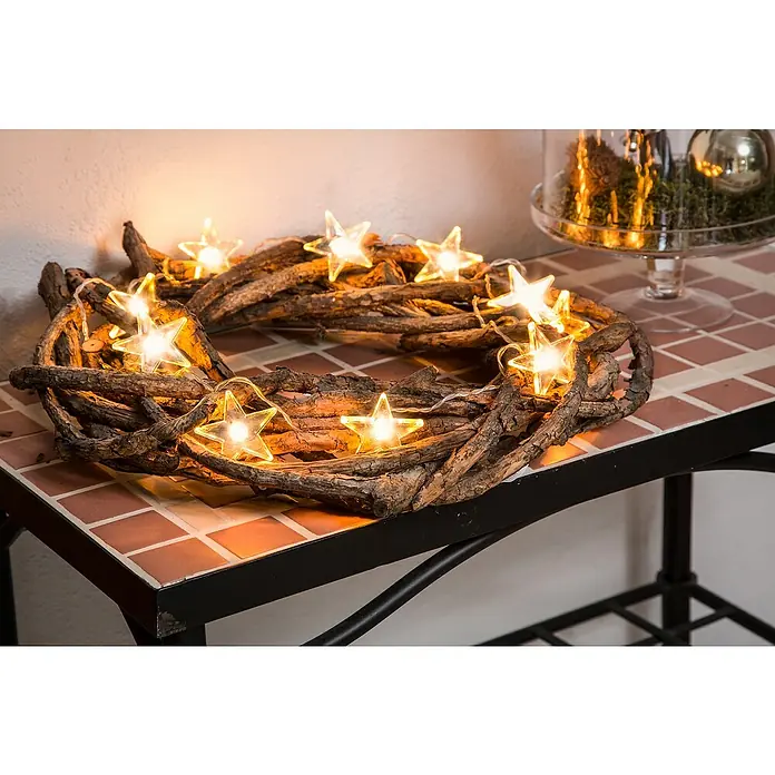 Konstsmide LED-Lichterkette Sterne - Innen, Lichtfarbe: Warmweiß, Anzahl Leuchtmittel: 10 Stk., Batteriebetrieben - Rustikaler Adventskranz aus Zweigen mit warm leuchtenden Sternenlichtern auf einem Mosaiktisch, festliche Dekoration für die Weihnachtszeit.