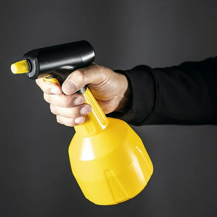 Mesto Drucksprüher e.FLOWER 3,7 V - Füllmenge: 1,5 l - Eine Hand hält eine gelbe Sprühflasche mit schwarzem Griff vor einem grauen Hintergrund.
