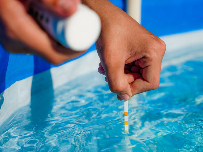 pH-Wert wird im Pool mit einem Teststäbchen gemessen 