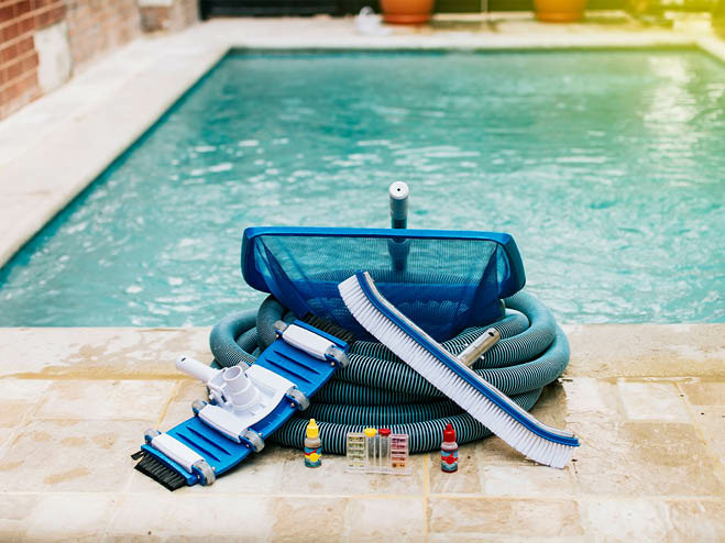 Poolsauger, Kescher, Schlauch und Co. liegen auf der Terrasse vor dem Einbaupool