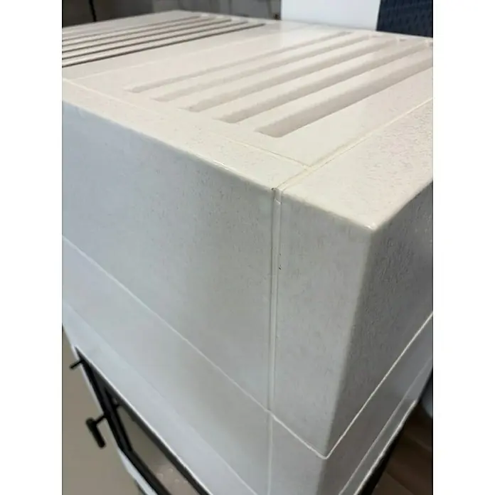 Domofire Kaminofen Erfurt links - 6 kW - Nahaufnahme eines Kaminofens mit weißer Verkleidung und Lüftungsschlitzen, der Wärme und Stil vereint.