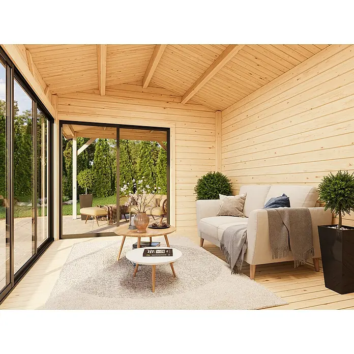 Palmako Gartenhaus Amanda Slide - Außenmaß inkl. Dachüberstand (B x T): 712 x 340 cm, Unbehandeltes Holz, Natur - Helle Holzterrasse mit gemütlicher Sitzecke, bestehend aus einem Sofa, Couchtisch und Pflanzen. Die großen Fenster bieten einen Blick in den Garten.