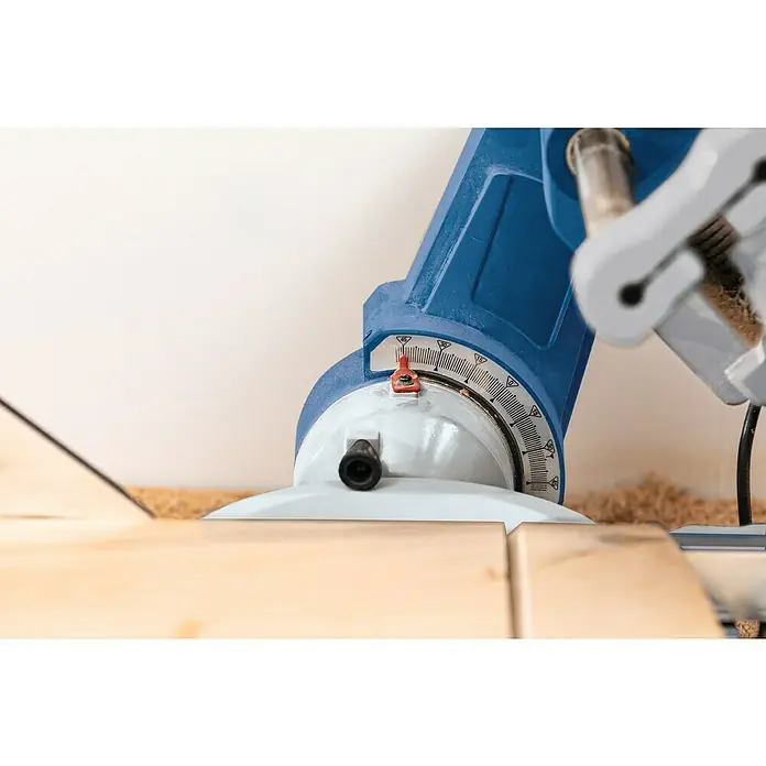 Scheppach Kapp- & Gehrungssäge HM305SL - 2.000 W, Durchmesser Sägeblatt: 305 mm, Leerlaufdrehzahl: 5.000 U/min - Nahaufnahme einer blauen Kappsäge beim Schneiden eines Holzstücks, wobei der Fokus auf dem Winkelmesser liegt.