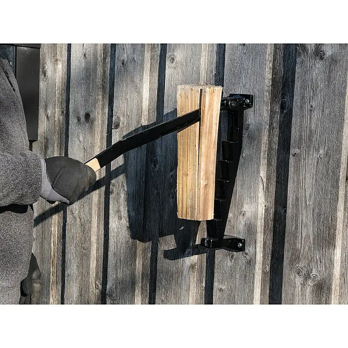 Scheppach Handholzspalter -  - Eine Person spaltet Holz mit einem an einer Holzwand montierten Holzspalter, wobei der Fokus auf der Funktion des Holzspalters liegt.