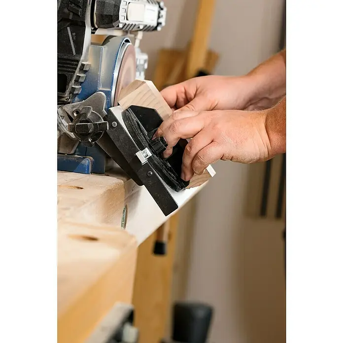 Scheppach Lijadora de banda y disco BTS900 - 370 W, 2.850 r.p.m. - Una persona lija una pieza de madera con una lijadora de banda. La máquina está sobre un banco de trabajo y la persona sujeta la pieza de madera.