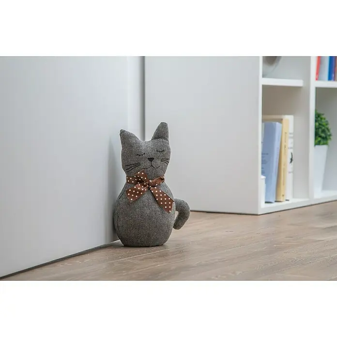 Rei Tope de puerta Gatito - Textil - Tope de puerta gris con forma de gato y un lazo marrón apoyado en la puerta.
