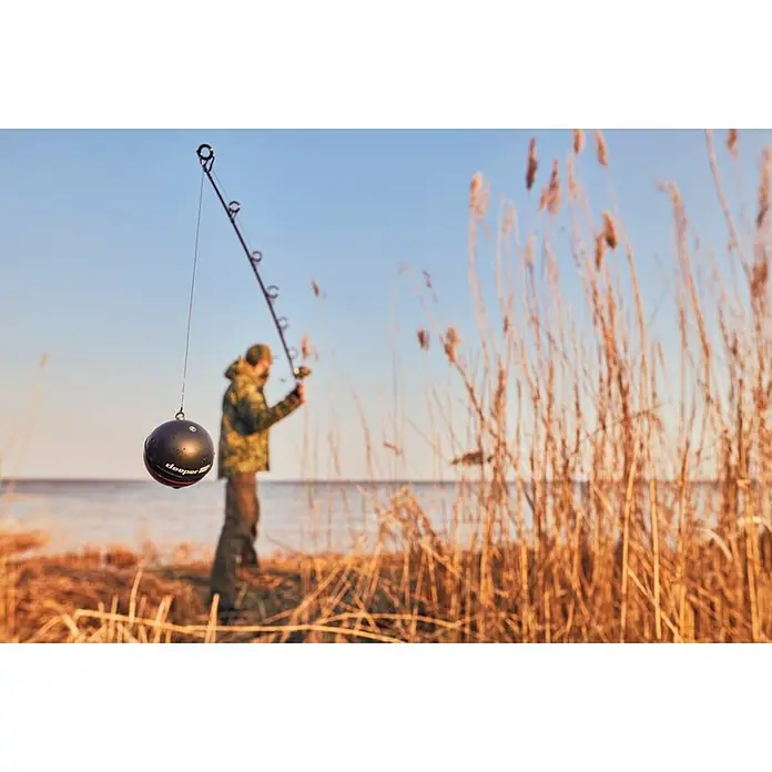 Deeper Fishfinder & GPS-Kartenplotter PRO+ 2 - Höhe: 65 mm, WLAN - Der Deeper Fischfinder hängt an einer Angel vor Schilf, bereit zum Einsatz. Das Gerät verspricht detaillierte Einblicke unter Wasser.