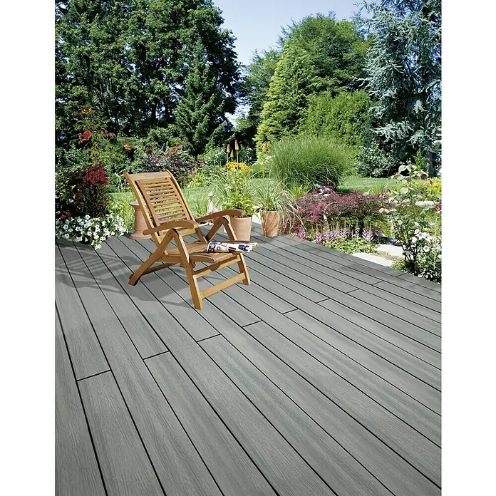 b!design WPC-Terrassendiele Mirage Grey - 300 x 13,8 x 2,25 cm, Grau - Eine graue Holzterrasse mit einem Liegestuhl aus Holz im Garten.
