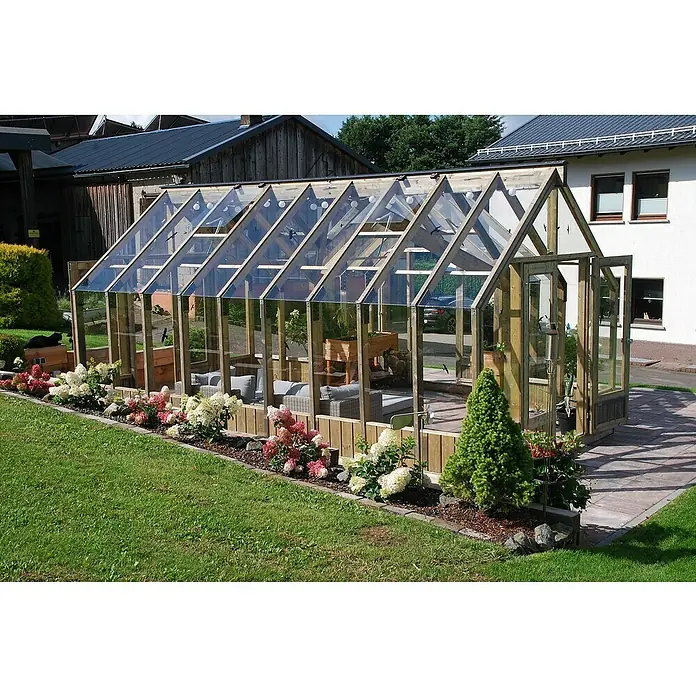 Palmako Invernadero Emilia XL - Medidas ext. (An x Pr): 421 x 543 cm, Madera, 18 mm, Gris - Un espacioso invernadero de madera y vidrio con plantas y muebles de jardín, rodeado de un jardín cuidado.