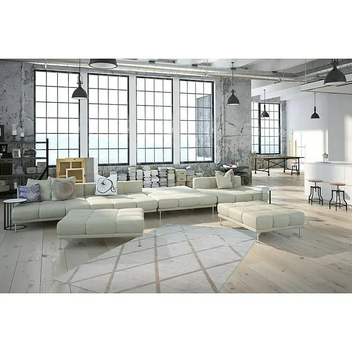 Kayoom Kurzflorteppich Luxury 210 - Elfenbein/Taupe, 150 x 80 cm, 100 % Viskose - Ein modernes Wohnzimmer mit einem großen, modularen Sofa und einem geometrischen Teppich, beleuchtet durch Hängelampen.