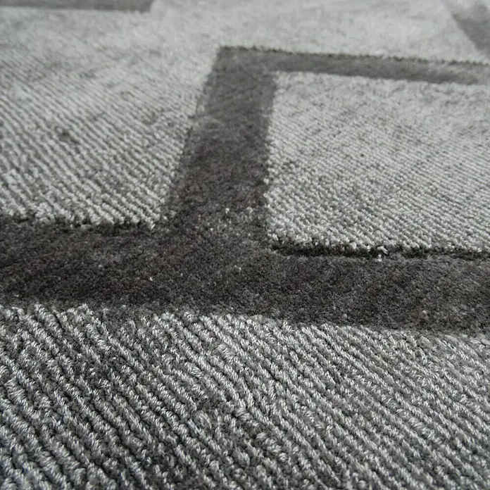 Kayoom Kurzflorteppich Luxury 310 - Grau, 150 x 80 cm, 100 % Viskose - Nahaufnahme eines grauen Teppichs mit einem geometrischen Muster, das eine subtile Textur und ein modernes Design aufweist.