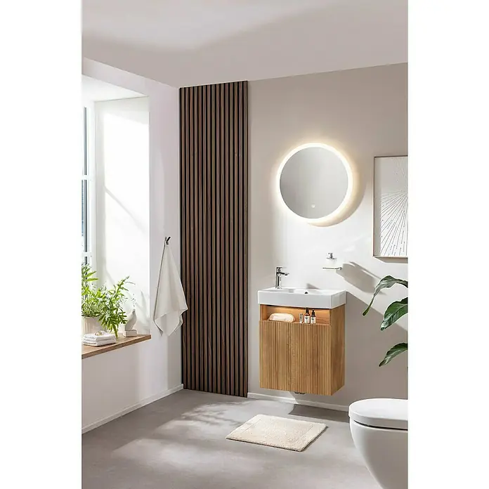 Camargue Pure Badmöbel-Set - Gesamtbreite Badmöbel: 55 cm, Berg Eiche, Matt - Elegantes Badezimmer-Interieur mit einem schwebenden Waschtisch aus Holz, einem runden Spiegel mit Beleuchtung und einer dekorativen Holzpaneelwand.