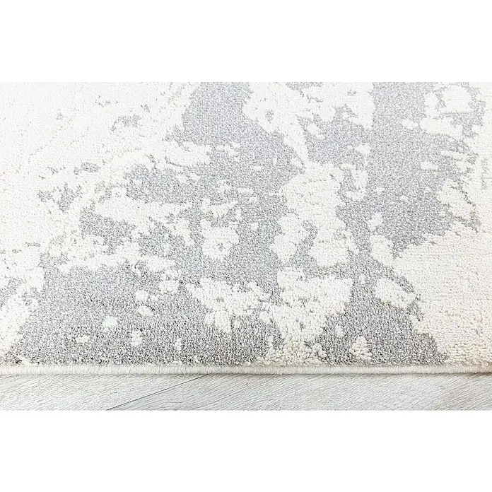 Alfombra de pelo corto Brochazos - Natural, 110 x 60 cm, 100% Poliéster - Primer plano de una alfombra moderna con un diseño abstracto en tonos grises y blancos.