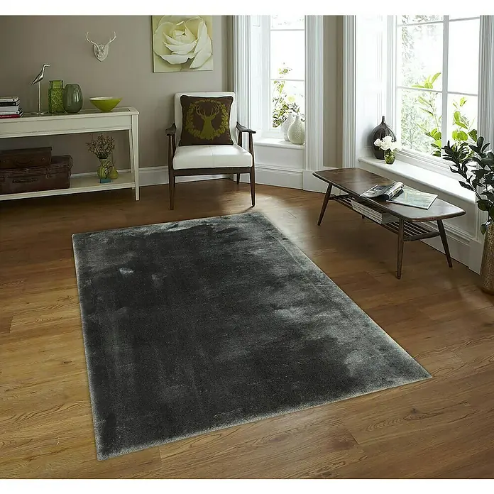 Alfombra de pelo largo Cuba - Gris, 110 x 60 cm, 100% Poliéster - Una alfombra gris con una textura suave está colocada sobre un suelo de madera en un salón elegante, aportando un toque elegante al espacio.