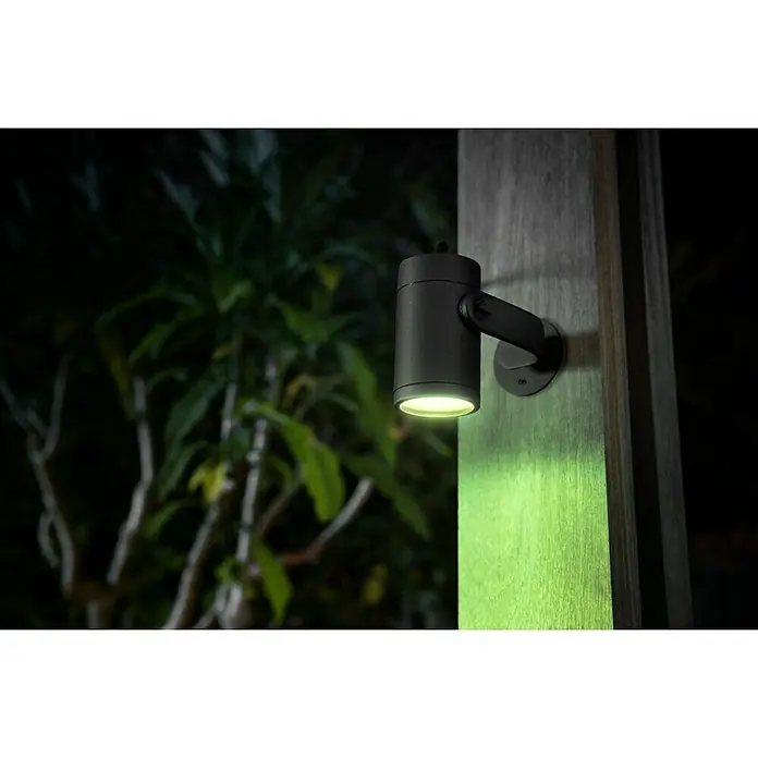 Philips Hue LED-Gartenspot Lily - 8 W, Lichtfarbe: RGB, IP65 - Nahaufnahme einer schwarzen Außenleuchte, die an einer Holzwand befestigt ist und ein warmes, einladendes Licht spendet.
