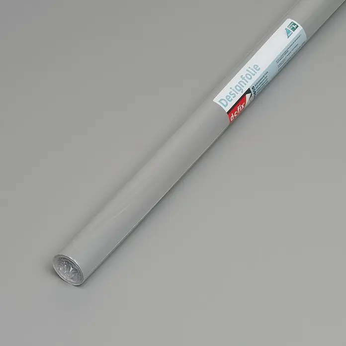 D-c-fix Klebefolie Uni Seidenmatt - 210 x 90 cm, Grau, Selbstklebend - Eine Rolle graue Designfolie der Marke d-c-fix liegt auf einer grauen Oberfläche. Ideal für DIY-Projekte und zur individuellen Gestaltung von Möbeln.