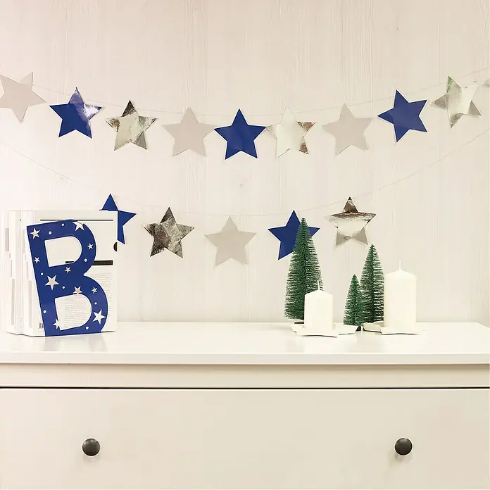 D-c-fix Metalleffektfolie Metallic Hochglanz - 150 x 45 cm, Silber, Selbstklebend - Dekorative Sternengirlande in Blau, Silber und Weiß, die eine festliche Atmosphäre schafft. Perfekt für Weihnachten und andere Feierlichkeiten.