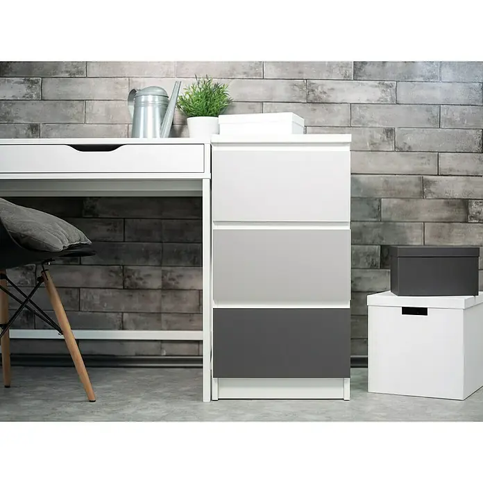 D-c-fix Klebefolie Uni Seidenmatt - 200 x 67,5 cm, Hellgrau, Selbstklebend - Nahaufnahme eines weißen Schreibtischs mit Schubladenelement und Dekorationsgegenständen vor einer Ziegelwand.