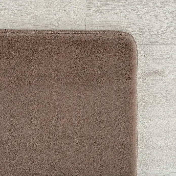 Kurzflorteppich Joy - Mokka, 100 x 60 cm, 100 % Polyester - Detailansicht eines braunen Shaggy-Teppichs, der auf einem hellen Holzboden liegt. Die weiche Textur des Teppichs ist gut erkennbar.