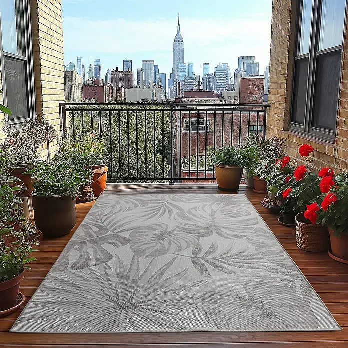Outdoor-Teppich Desert 1302 - Grau, 290 x 200 cm, 100 % Polypropylen - Balkon mit gemustertem Teppich und Blick auf die Skyline.