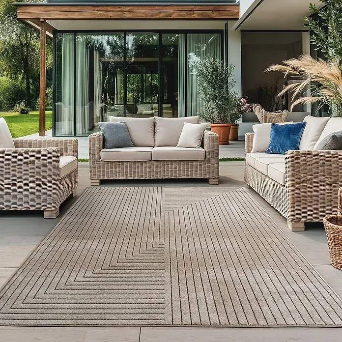 Outdoor-Teppich Nova II - Beige, 230 x 160 cm, 100 % Polypropylen - Moderner Outdoor-Teppich mit geometrischem Muster, umgeben von Rattanmöbeln auf einer Terrasse.