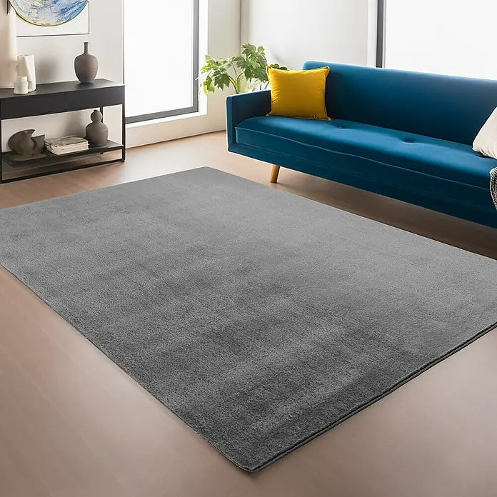 Kurzflorteppich Joy - Grau, 280 x 200 cm, 100 % Polyester - Ein grauer Teppich liegt in einem Wohnzimmer mit blauer Couch und schwarzen Möbeln. Der weiche Teppich sorgt für Komfort und Stil im Raum.