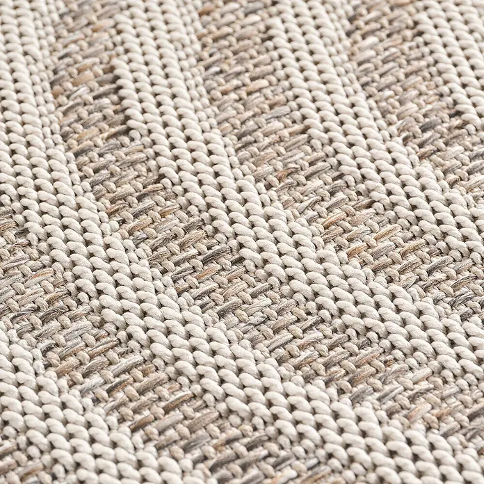 Outdoor-Teppich Desert 1301 - Beige, Durchmesser: 120 cm, 100 % Polypropylen - Nahaufnahme eines gewebten Teppichs mit einer Textur aus hellen und dunklen Fasern, die ein subtiles Muster bilden.